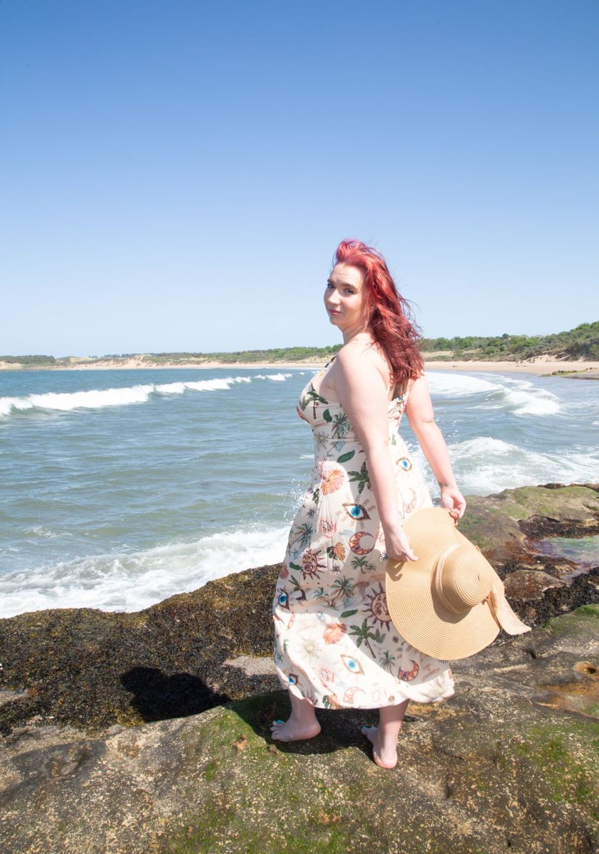 Business owner holding a sun hat on the rocks by the sea